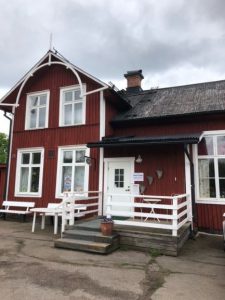 Ett rött gammalt stationshus hus med vita fönster där Hållplats loppis har sin verksamhet.