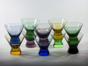 Glas med en mindre fot. Glasen är i färgerna blå, grön, gul och lila.