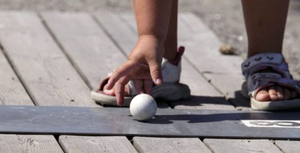 En barnhand som sträcker sig efter en bangolfboll.