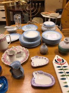 Bord med diverse porslin i rosa och blått på. På bordet finns även tre vaser, en såsnipa, en kandelaber och en kaffekanna.