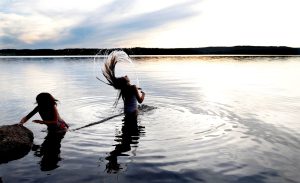 Två barn som badar i en sjö i solnedgången. 