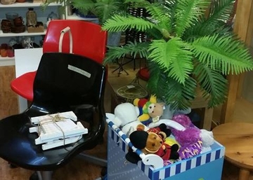Två stolar. En palm i plast. En låda med gose- och leksaksdjur.