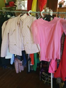 Rosa blus och vit jacka hängandes på ett klädställ